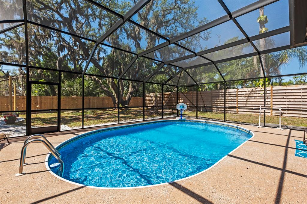 An oval swimming pool is enclosed by a screened lanai with a concrete pool deck — 2352 PALM TERRACE, SARASOTA, FL