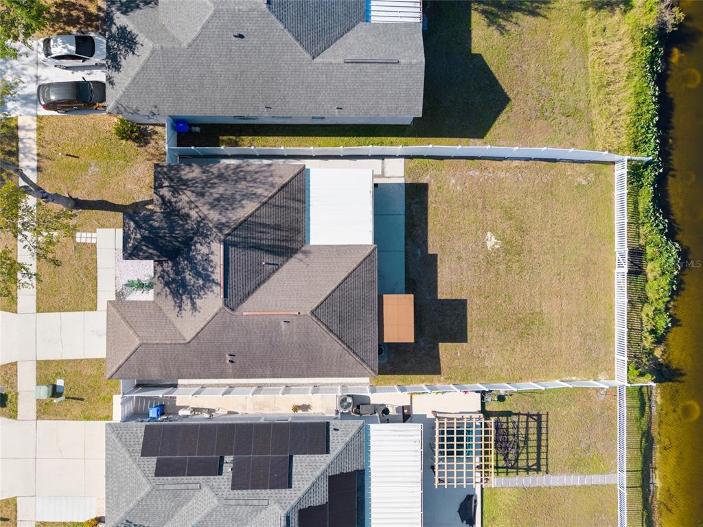 An aerial view shows two adjacent houses with backyards, a white fence, and a pond — 1305 FLEXFORD STREET, BRANDON, FL