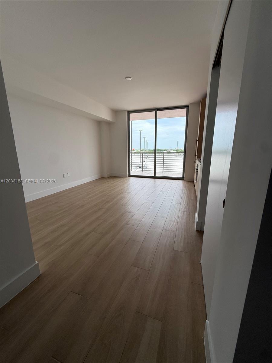 An empty room with light wood-look flooring and a sliding glass door to a balcony — 90 NE 32 street # 623, Miami FL 33127, MIAMI, FL