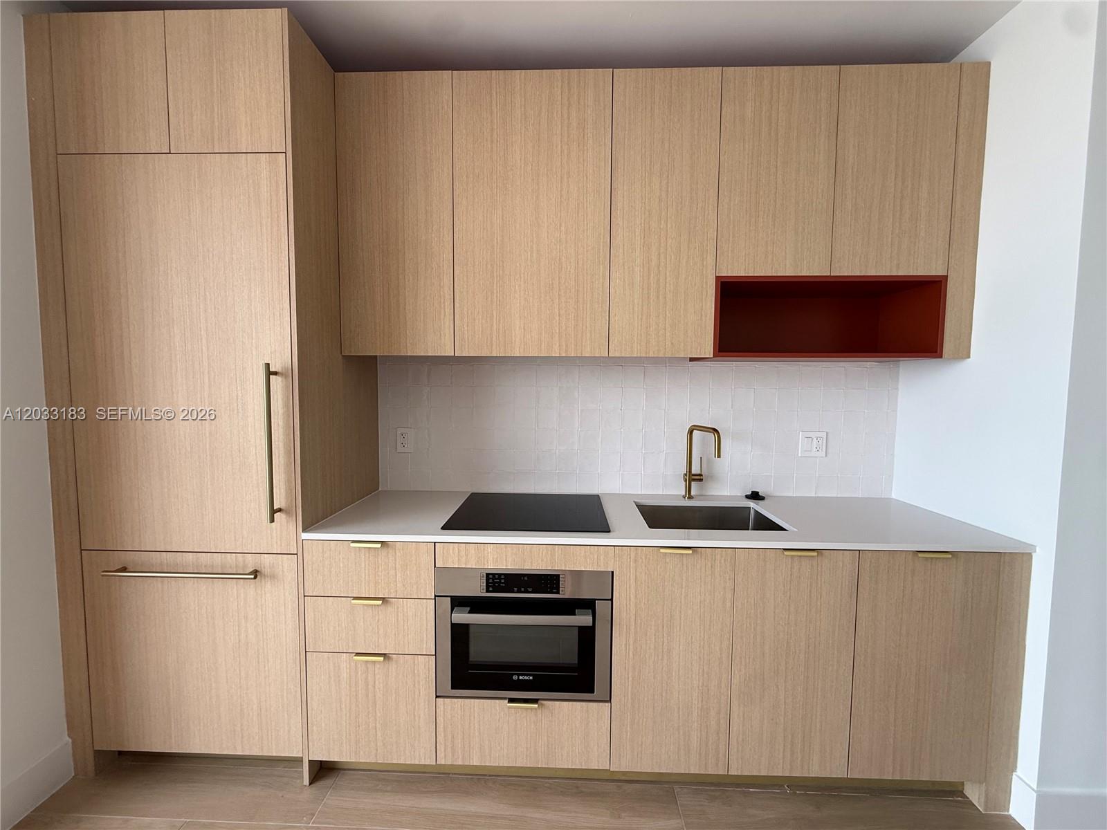 A modern kitchen features light wood cabinetry, a white tile backsplash, and a red shelf — 90 NE 32 street # 623, Miami FL 33127, MIAMI, FL