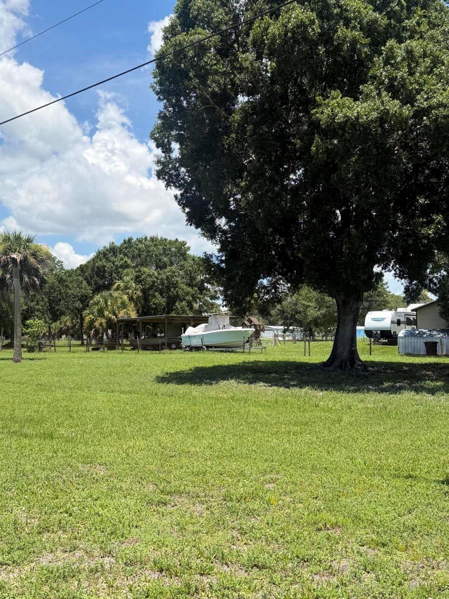 A grassy yard features a large tree, a boat under a shelter, and a camper — 0 NE 28th Avenue, Okeechobee FL 34972, OKEECHOBEE, FL