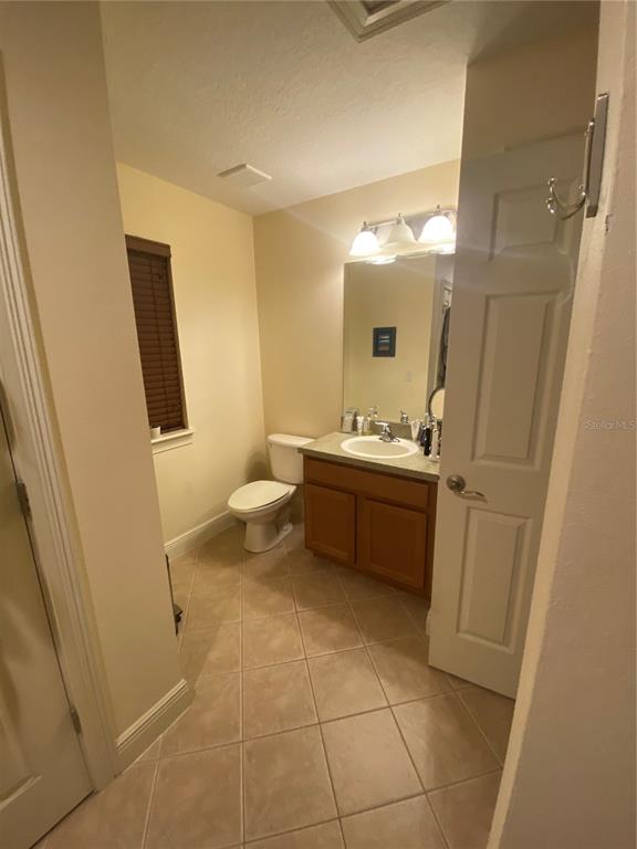 A bathroom features a vanity with a sink, a toilet, and light-colored tile flooring — 2892 LINCROFT AVENUE UNIT 2, ORLANDO, FL