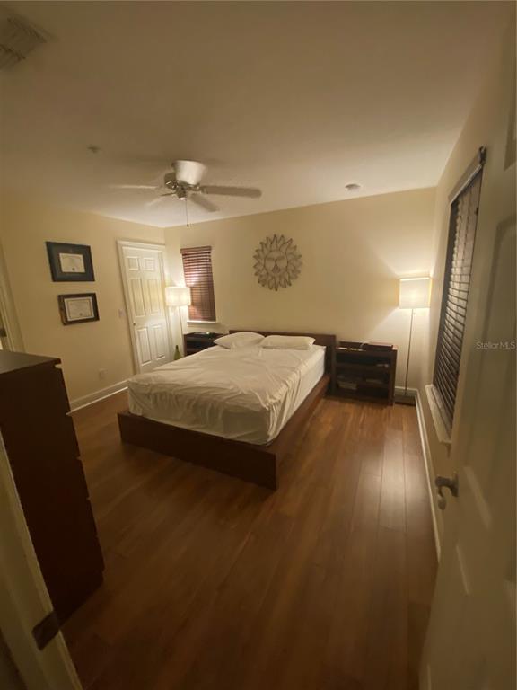 A bedroom with wood-look flooring, a platform bed, a ceiling fan, and two floor lamps — 2892 LINCROFT AVENUE UNIT 2, ORLANDO, FL