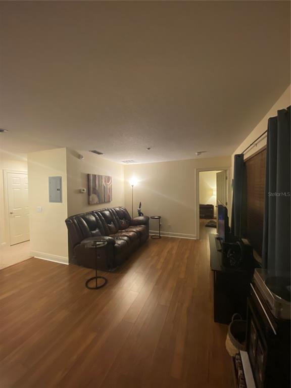 A living room features wood-look flooring, a brown leather sofa, and a doorway to another room — 2892 LINCROFT AVENUE UNIT 2, ORLANDO, FL