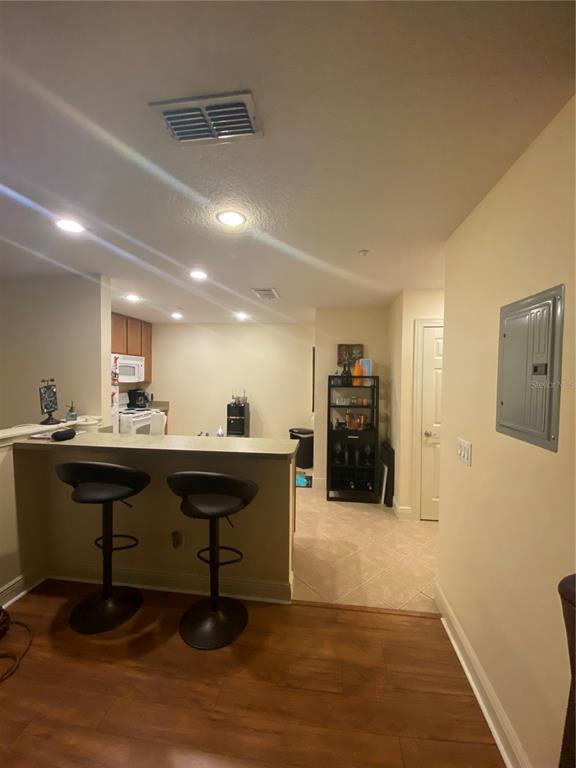 A kitchen with a breakfast bar, two stools, and a wooden floor in the foreground — 2892 LINCROFT AVENUE UNIT 2, ORLANDO, FL