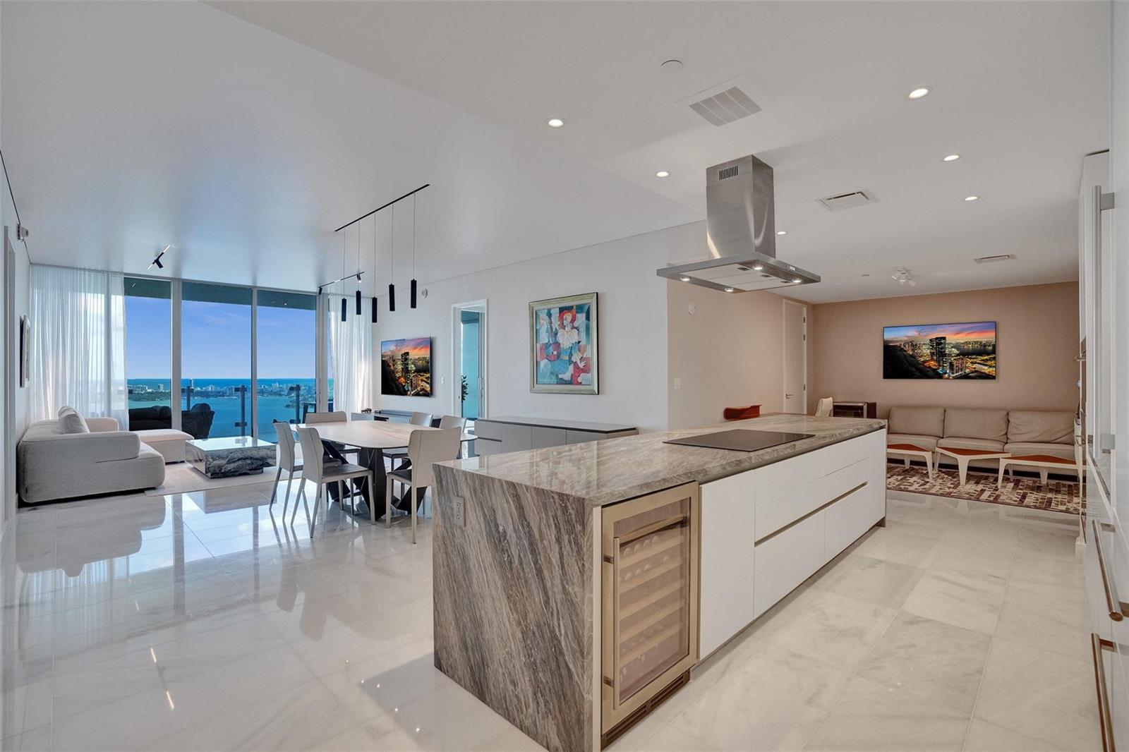A modern open-concept kitchen and living area features a marble island, white cabinetry, and ocean views — 700 NE 26th Terrace # 4702, Miami FL 33137, MIAMI, FL