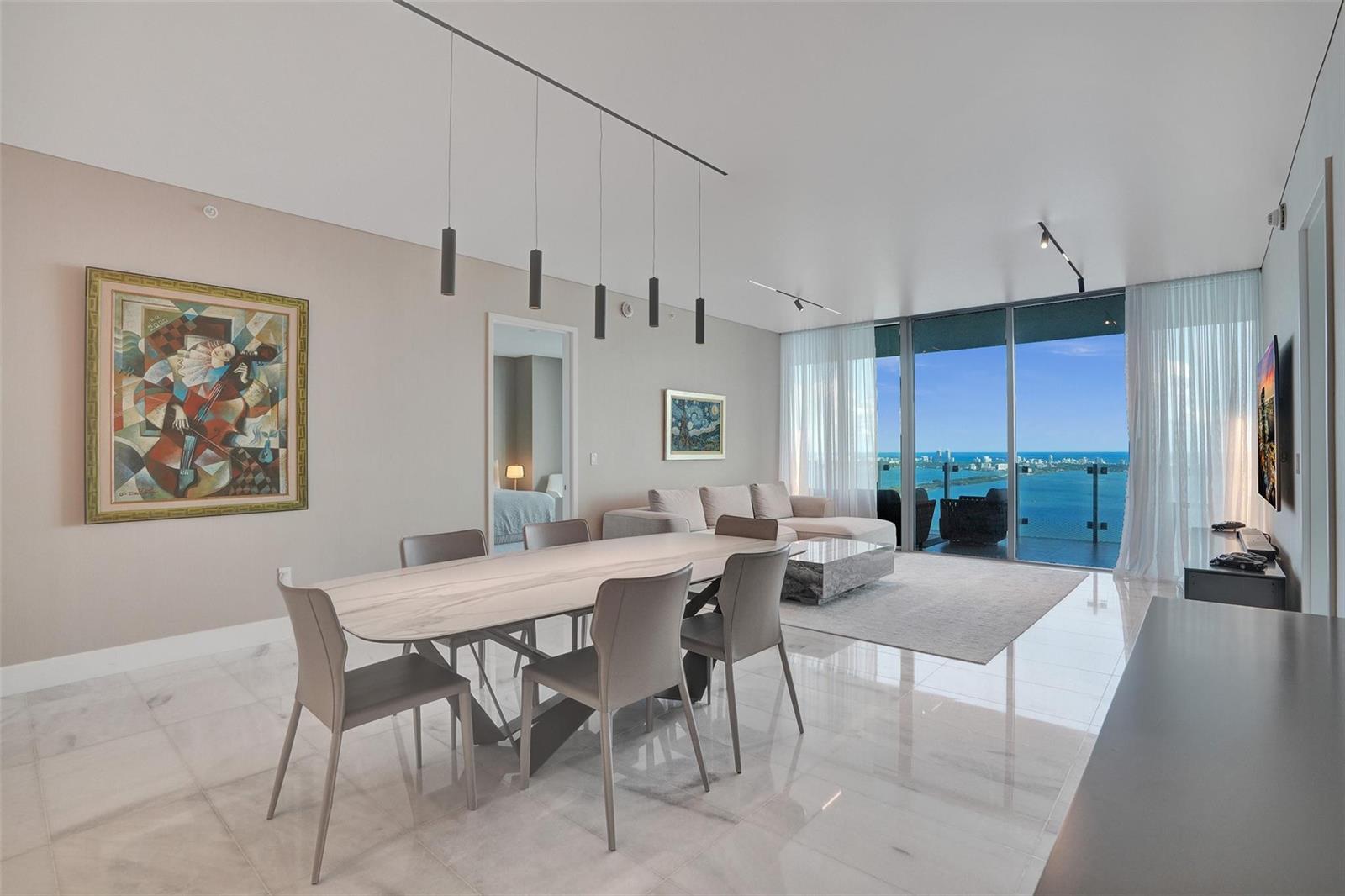 A modern dining and living area features marble floors, a balcony, and ocean views — 700 NE 26th Terrace # 4702, Miami FL 33137, MIAMI, FL