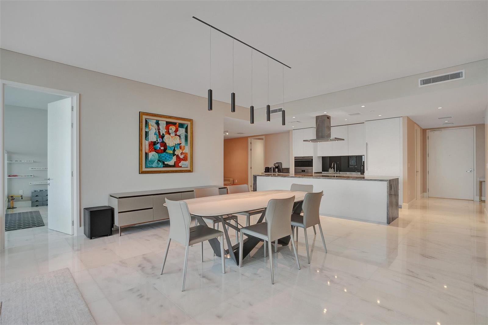 A modern dining area with a marble floor, rectangular table, and pendant lighting near a kitchen — 700 NE 26th Terrace # 4702, Miami FL 33137, MIAMI, FL