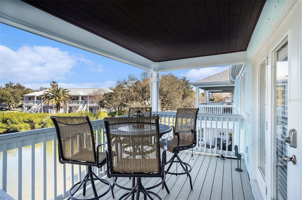 A covered balcony features a dining set, white railings, and views of surrounding residential buildings — 5176 SALMON DRIVE SE UNIT D, ST PETERSBURG, FL