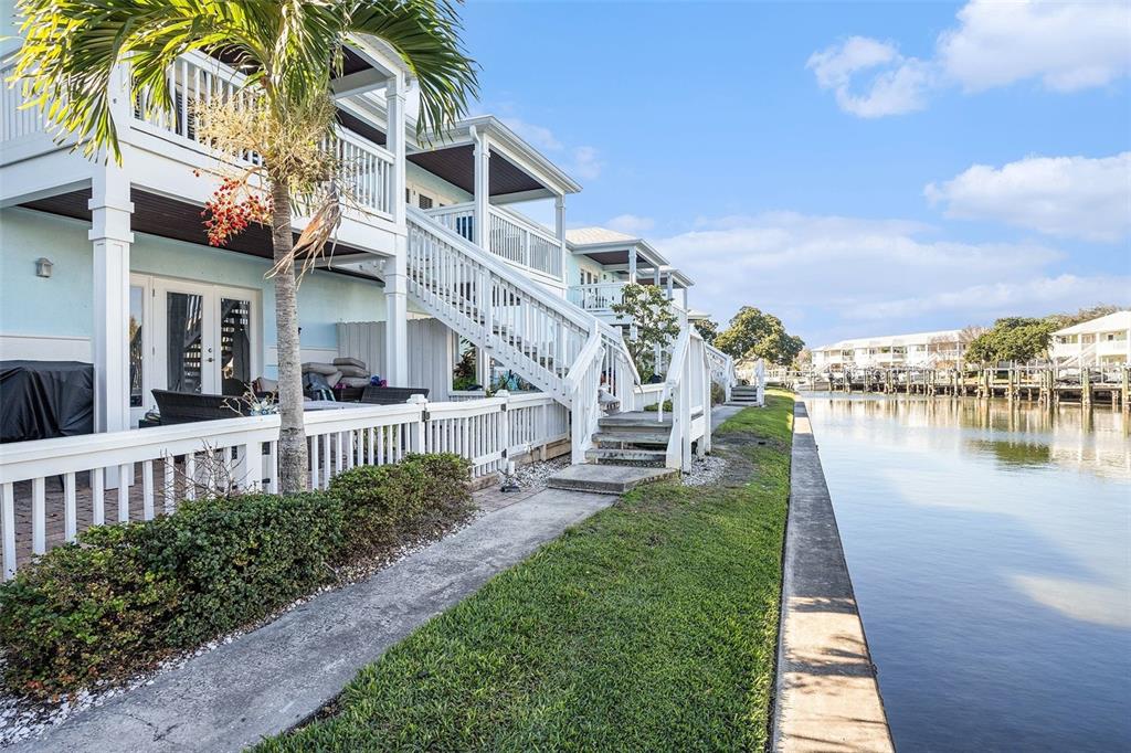 A multi-story waterfront townhouse with a white staircase, patio, and canal view — 5176 SALMON DRIVE SE UNIT D, ST PETERSBURG, FL
