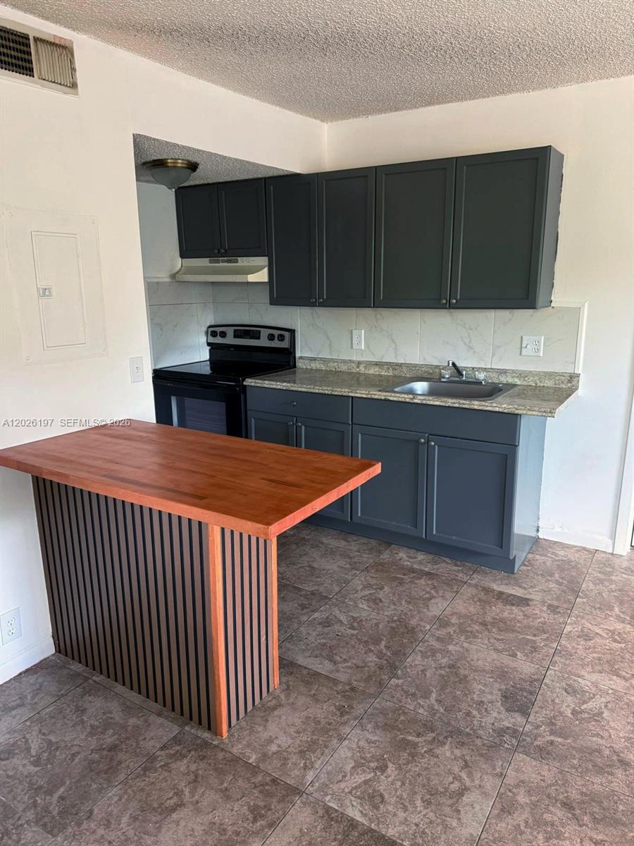 A kitchen features dark gray cabinets, a wood-topped island, and tiled flooring — 2070 NW 43rd Ter # 6, Lauderhill FL 33313, LAUDERHILL, FL