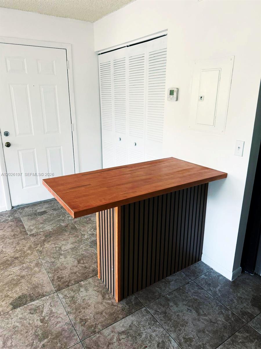 A kitchen island with a wood countertop stands on a tiled floor near a door — 2070 NW 43rd Ter # 6, Lauderhill FL 33313, LAUDERHILL, FL