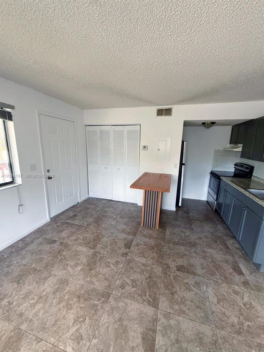 A kitchen with gray cabinets, tile flooring, and a small wooden breakfast bar — 2070 NW 43rd Ter # 6, Lauderhill FL 33313, LAUDERHILL, FL