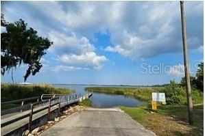 A concrete boat ramp leads into a lake next to a metal pedestrian dock — 455 NICHELE BOULEVARD, LAKE PLACID, FL