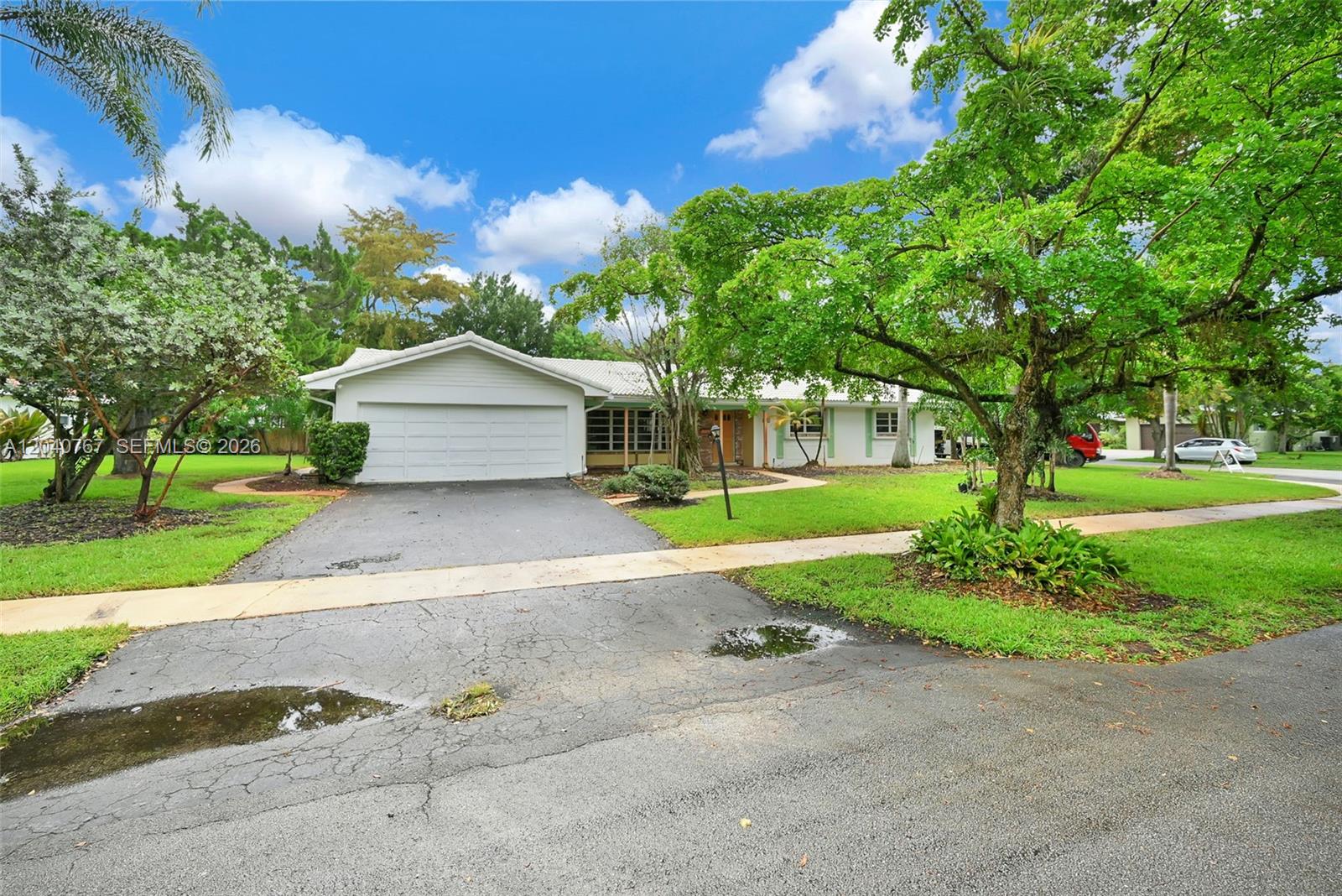 A single-story house with a white garage, a paved driveway, and mature trees in front — 600 Petunia Dr, Plantation FL 33317, PLANTATION, FL