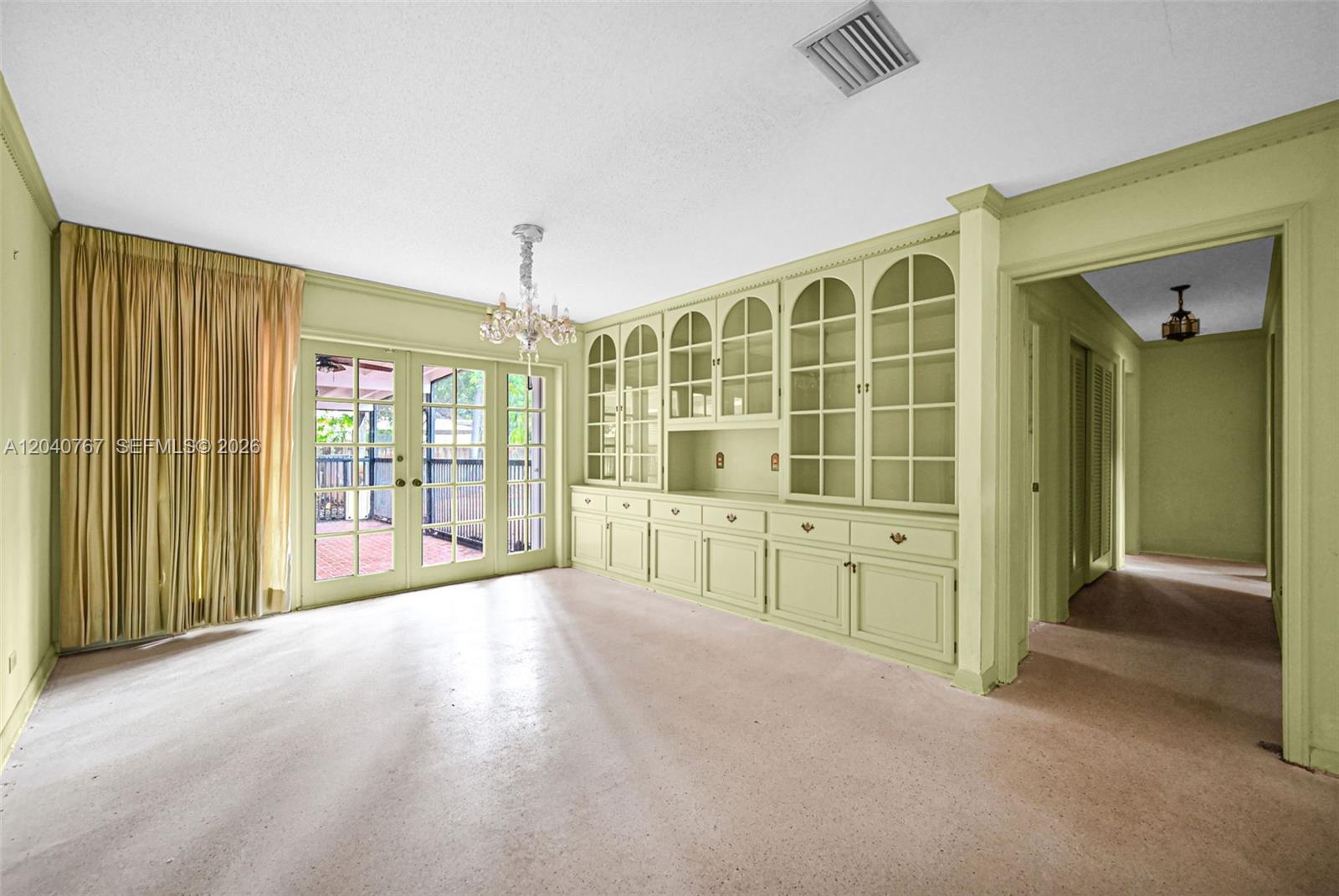 A room with light green walls, built-in cabinetry, a chandelier, and glass doors to a patio — 600 Petunia Dr, Plantation FL 33317, PLANTATION, FL