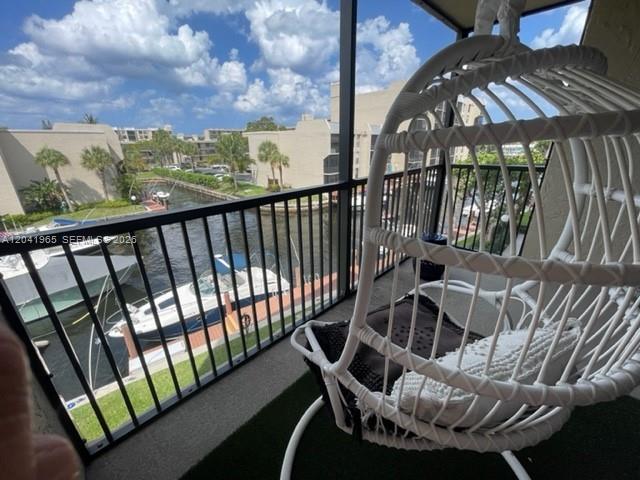 A balcony with a white hanging chair overlooks a canal with docked boats — 17 Royal Palm Way # 302, Boca Raton FL 33432, BOCA RATON, FL