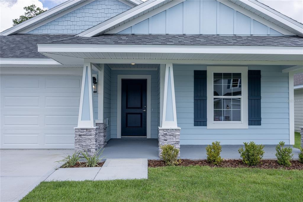 The exterior of a light blue house features a covered porch with stone-based columns — 2602 SW 250TH TERRACE, NEWBERRY, FL
