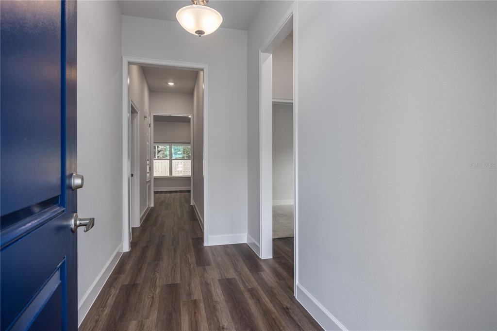 A hallway with wood-look flooring leads to an interior room with a window — 2602 SW 250TH TERRACE, NEWBERRY, FL