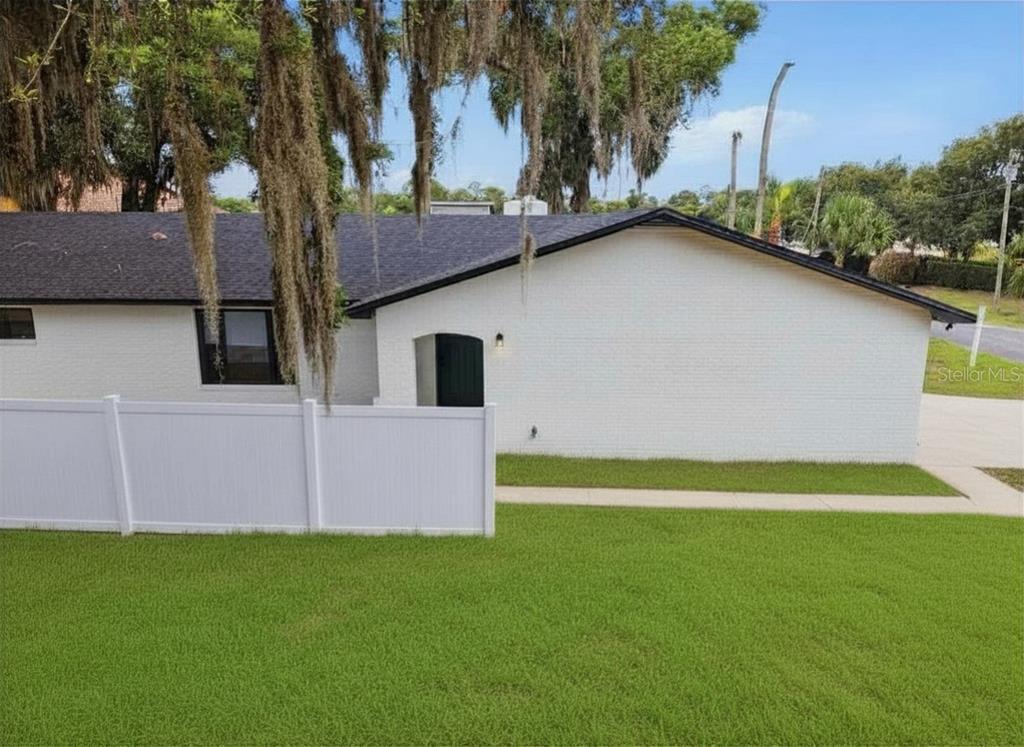 A white brick house exterior features a dark roof, a black door, and a white fence — 107 S HIGH STREET, LAKE MARY, FL