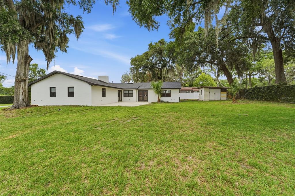 A white single-story house with a dark roof sits on a large grassy lawn — 107 S HIGH STREET, LAKE MARY, FL