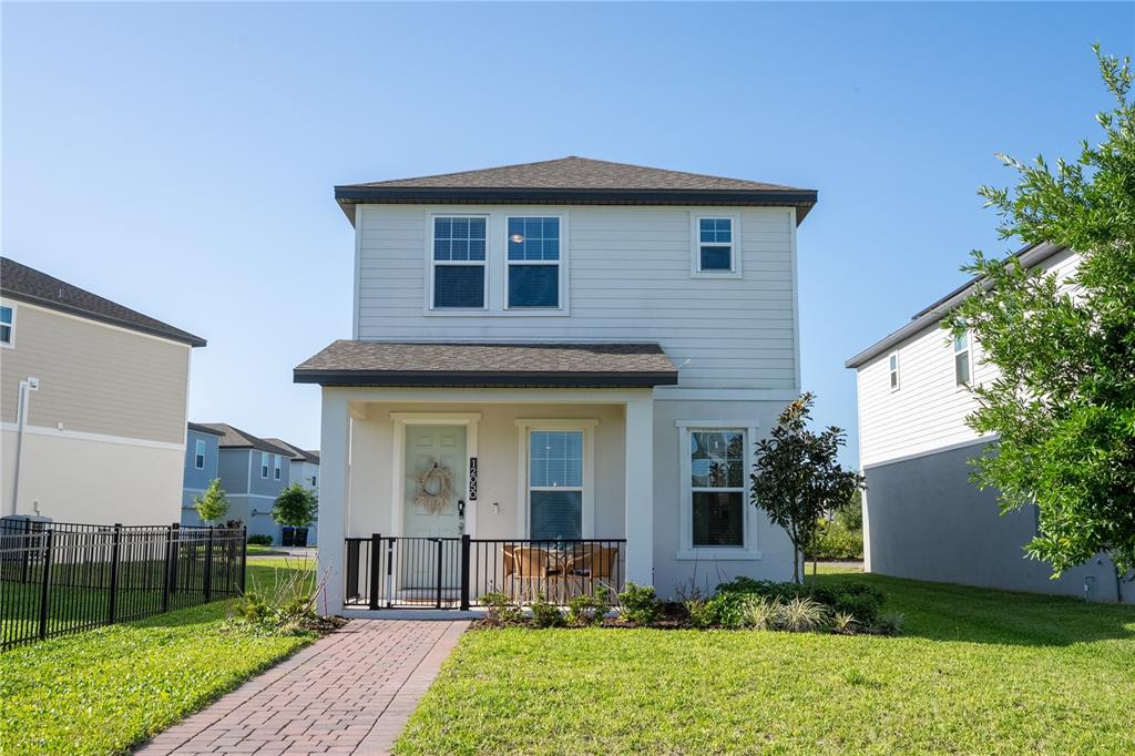 A two-story house with light siding, a covered front porch, and a brick walkway — 12050 BRACCO STREET, WINTER GARDEN, FL