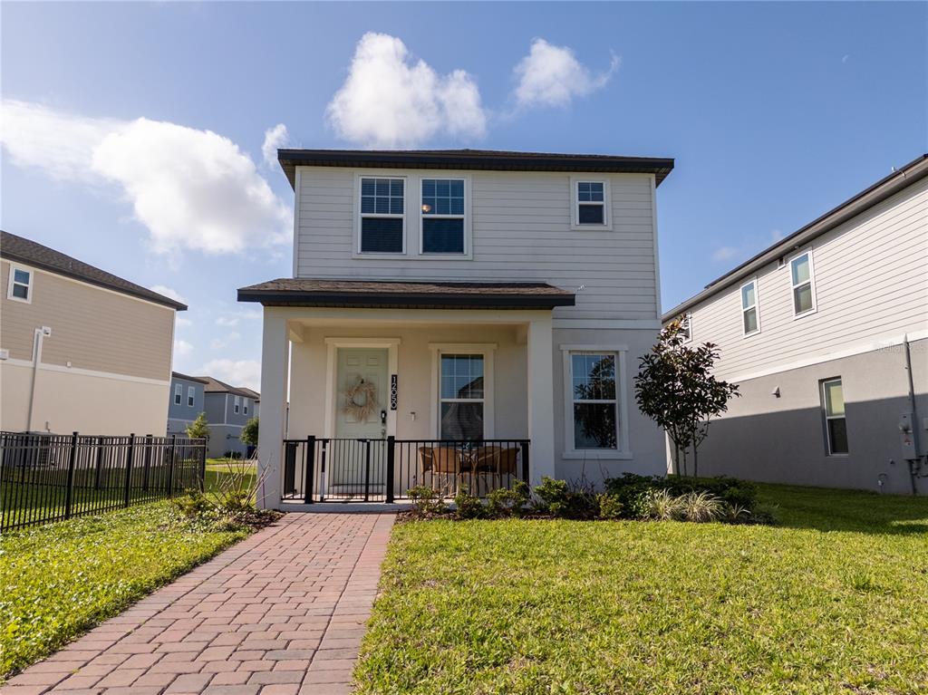 A two-story house with light siding, a front porch, and a brick walkway — 12050 BRACCO STREET, WINTER GARDEN, FL