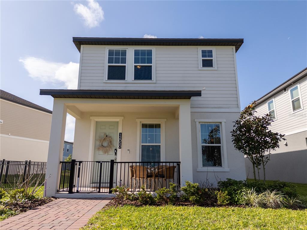 A two-story house with light siding, a covered front porch, and a brick walkway — 12050 BRACCO STREET, WINTER GARDEN, FL