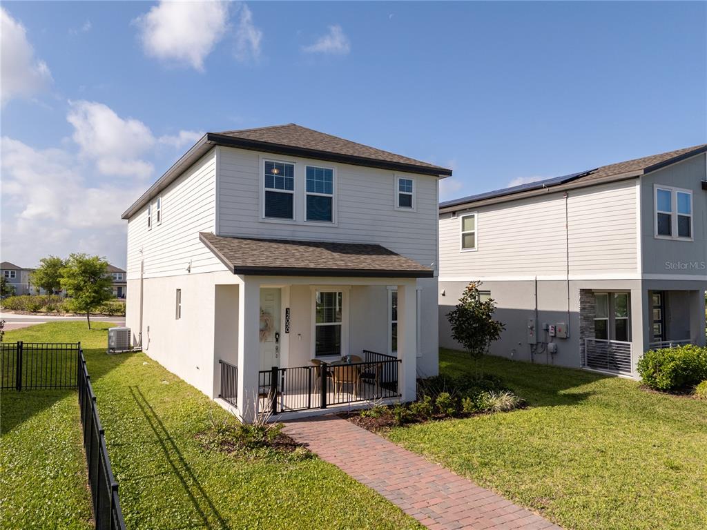 A two-story house with light-colored siding features a front porch and a brick walkway — 12050 BRACCO STREET, WINTER GARDEN, FL