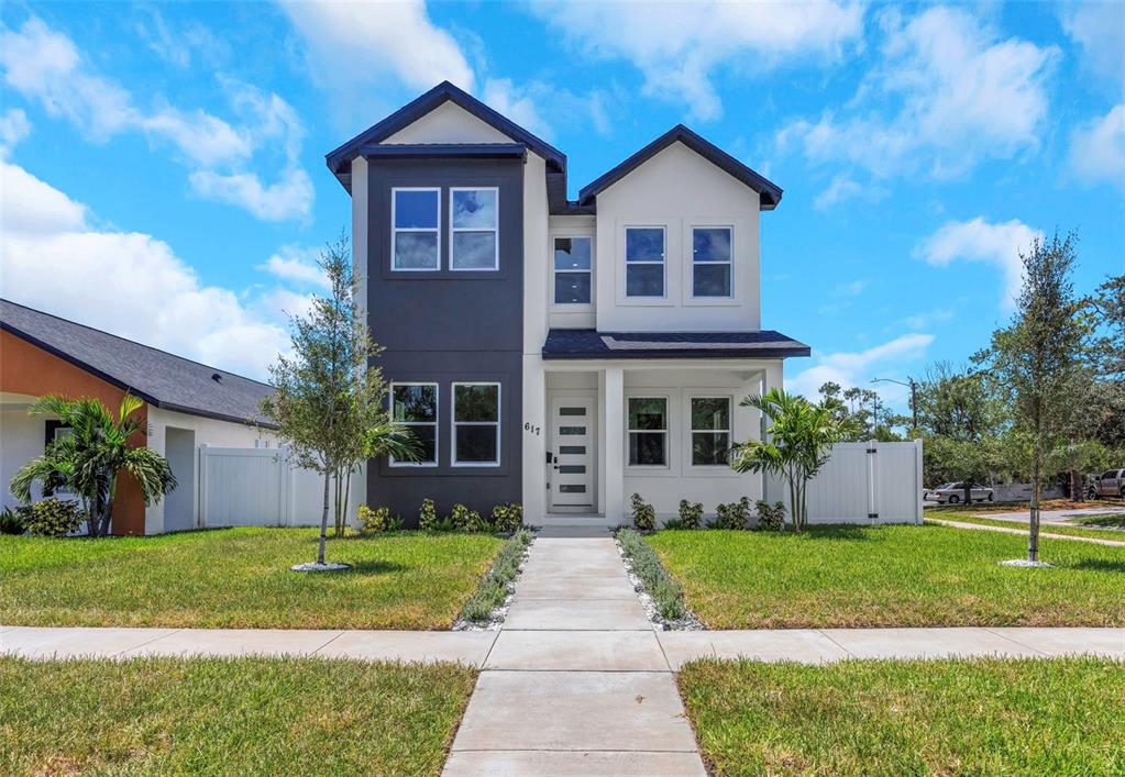 A two-story house with a dark gray and white exterior stands behind a concrete walkway — 617 FOLSOM STREET S, ST PETERSBURG, FL