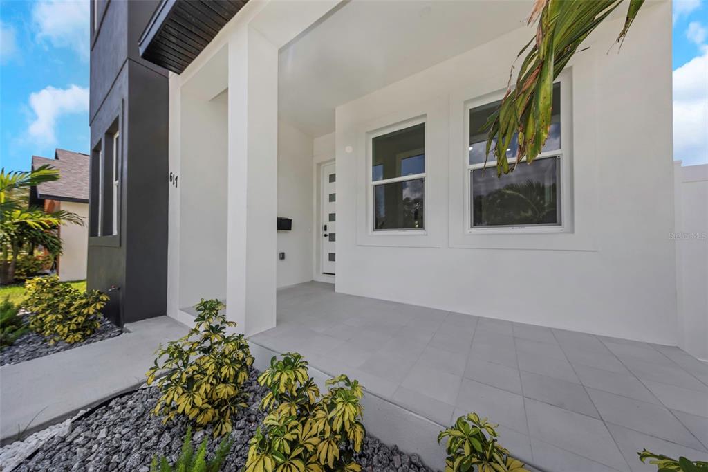 A modern home exterior features a white covered porch, tiled floor, and a front door — 617 FOLSOM STREET S, ST PETERSBURG, FL