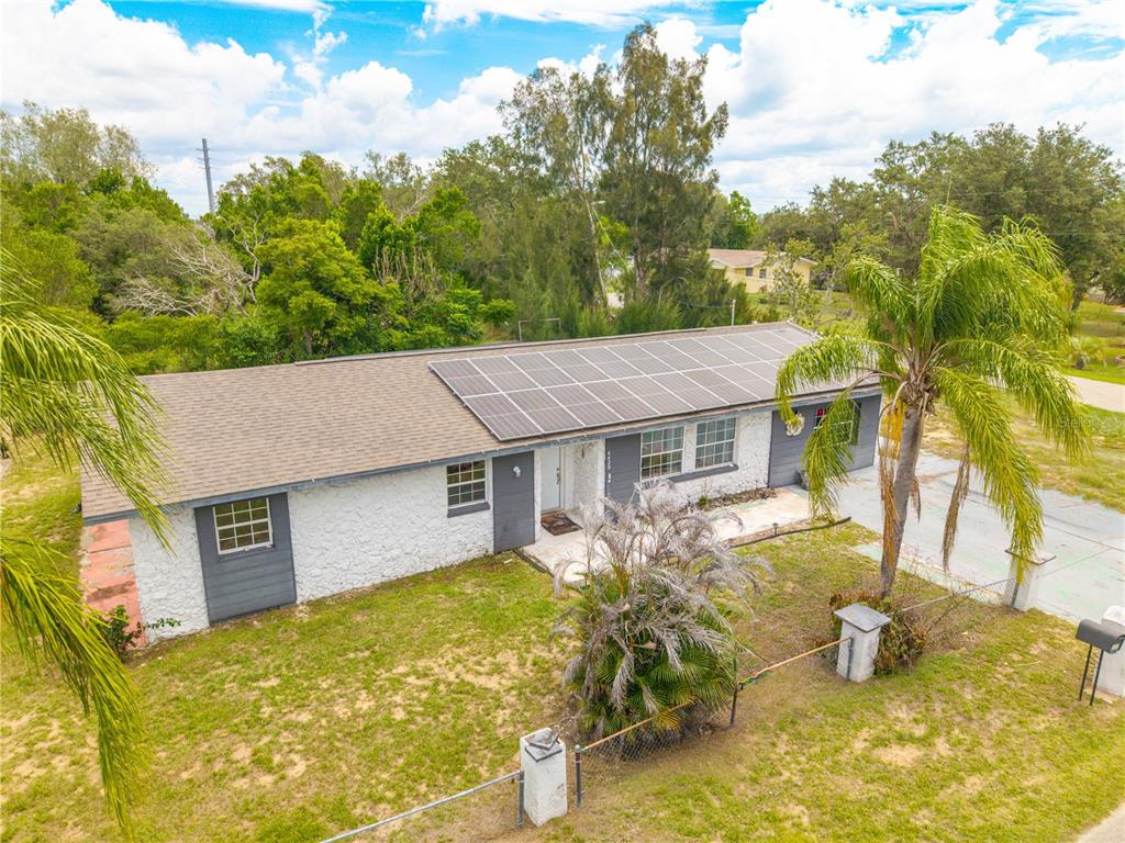 An exterior view of a single-story house with a solar panel array on the roof — 4420 AVISTA STREET, SEBRING, FL