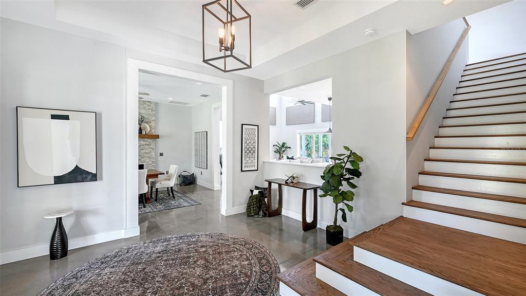 A foyer features a circular rug, a wooden staircase, and a view into a dining area — 1408 OAK HAMMOCK ROAD, SARASOTA, FL