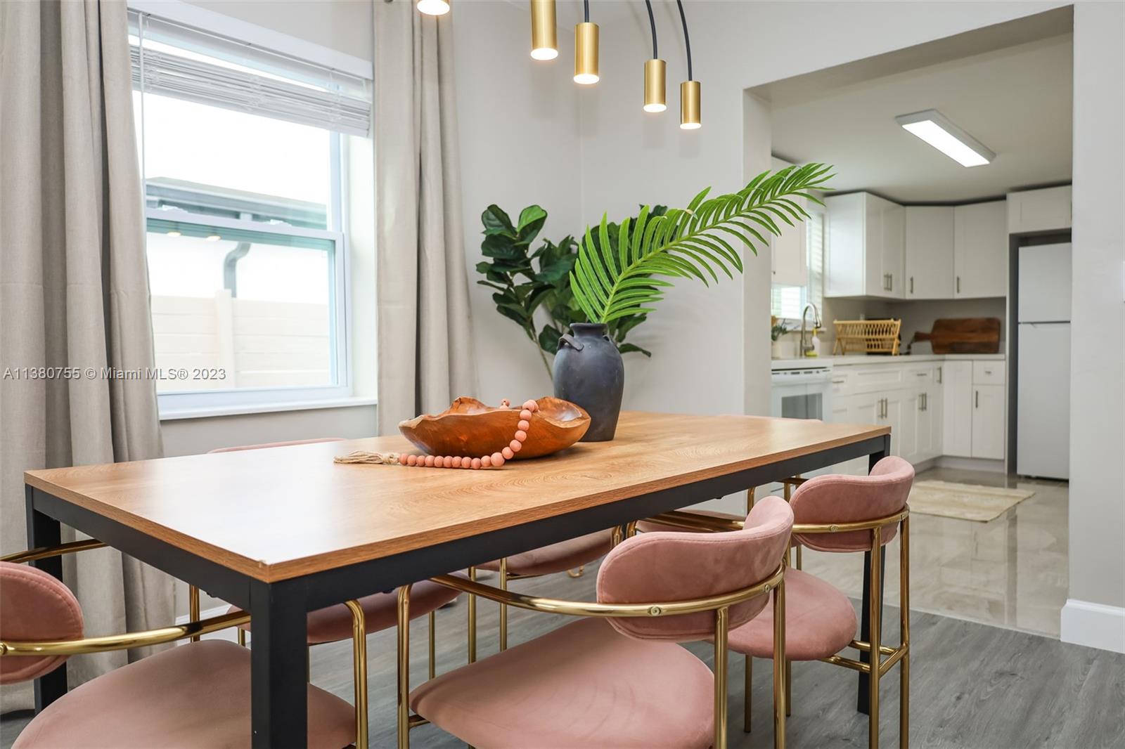 A dining room features a wooden table with pink velvet chairs and a modern light fixture — 2761 SW 33rd Ave # 1, Miami FL 33133, MIAMI, FL