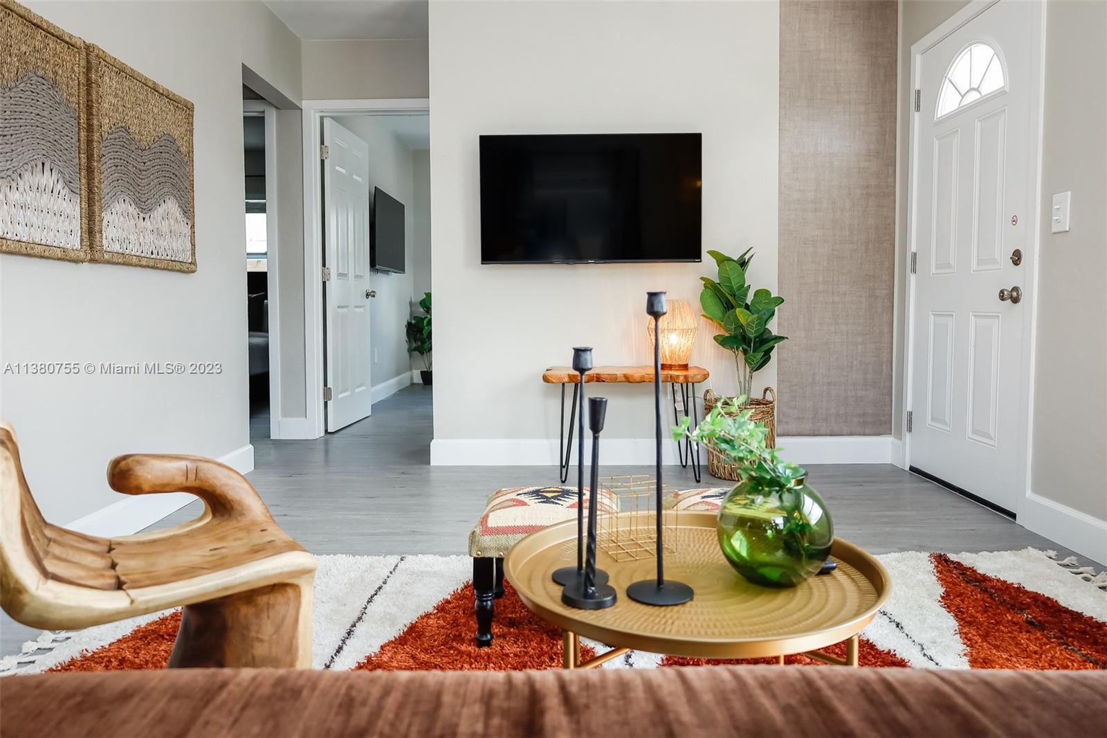 A living room features a wall-mounted television, a gold coffee table, and a wooden chair — 2761 SW 33rd Ave # 1, Miami FL 33133, MIAMI, FL