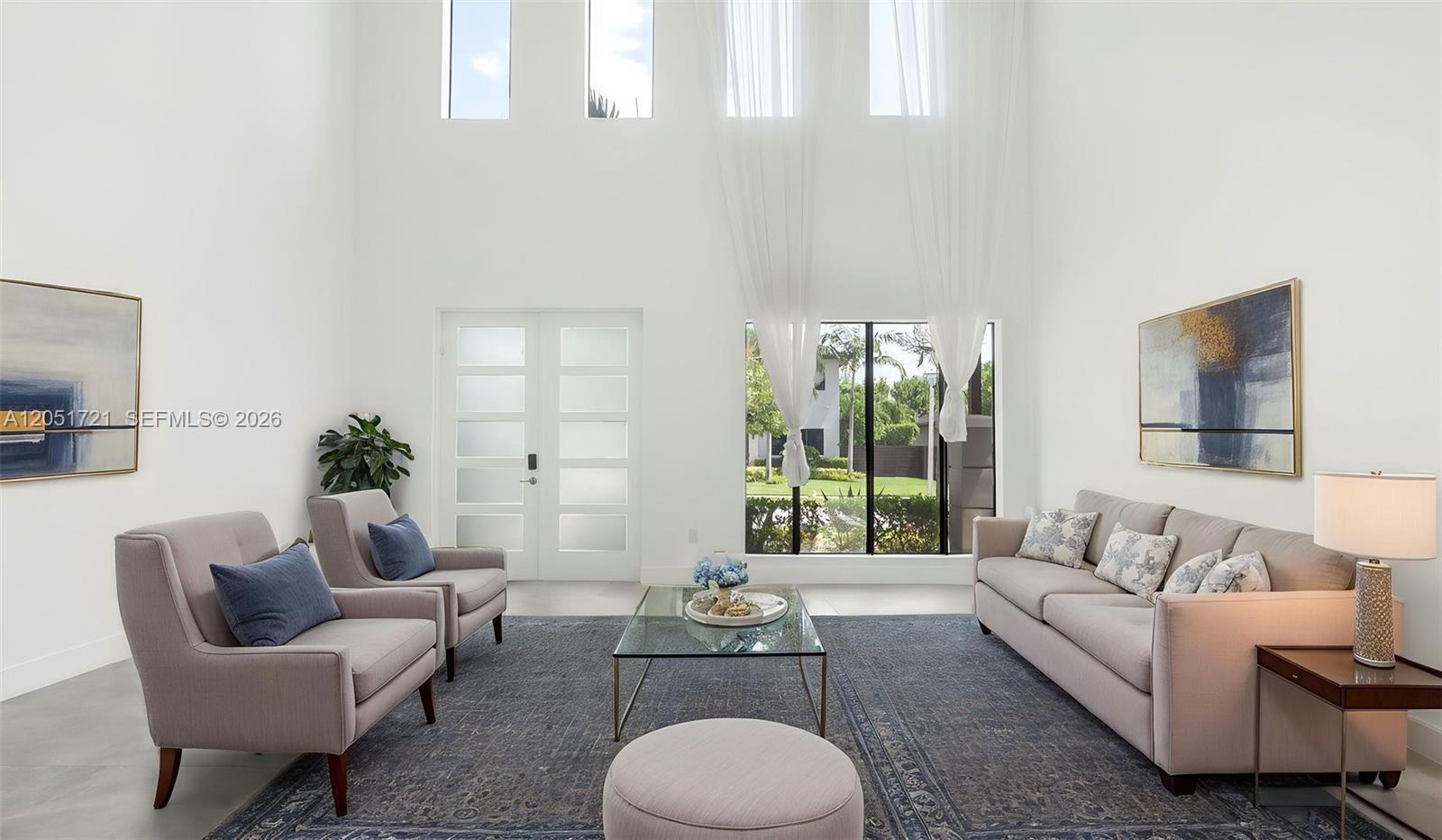 A high-ceilinged living room features a sofa, two armchairs, a glass coffee table, and artwork — 8900 NW 161st Ter, Miami Lakes FL 33018, MIAMI LAKES, FL