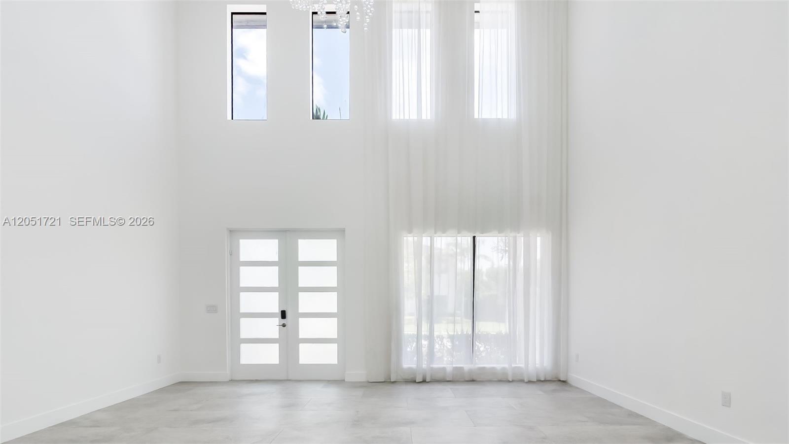 A bright, high-ceilinged entryway features white walls, large windows with sheer curtains, and tile flooring — 8900 NW 161st Ter, Miami Lakes FL 33018, MIAMI LAKES, FL