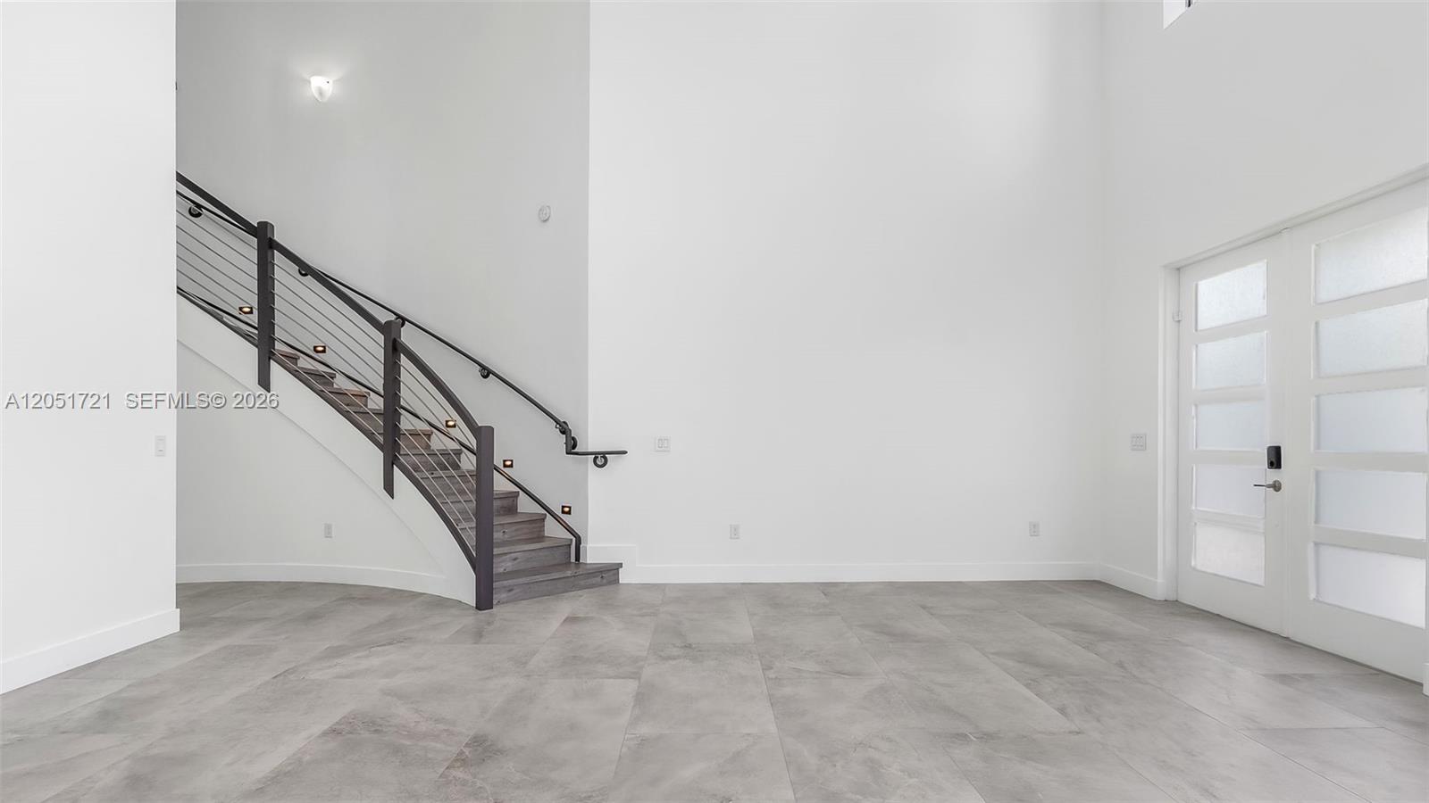 An entryway features a curved staircase with metal railings, gray tile flooring, and white walls — 8900 NW 161st Ter, Miami Lakes FL 33018, MIAMI LAKES, FL