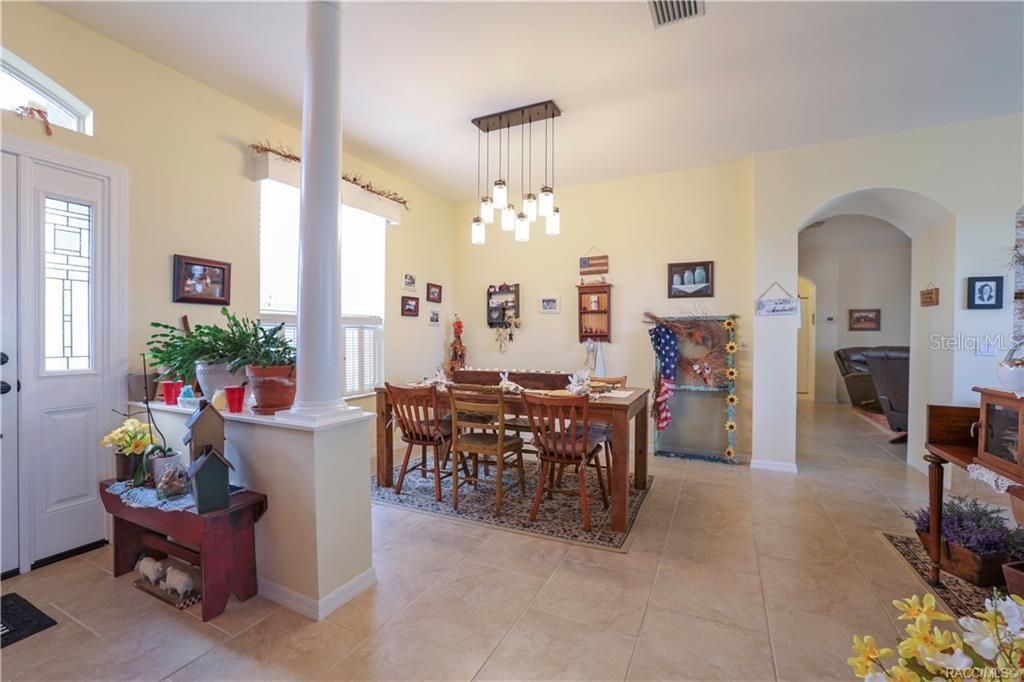 A dining area with a wooden table, pendant lighting, and tile flooring near an entryway — 209 W REXFORD DRIVE, BEVERLY HILLS, FL