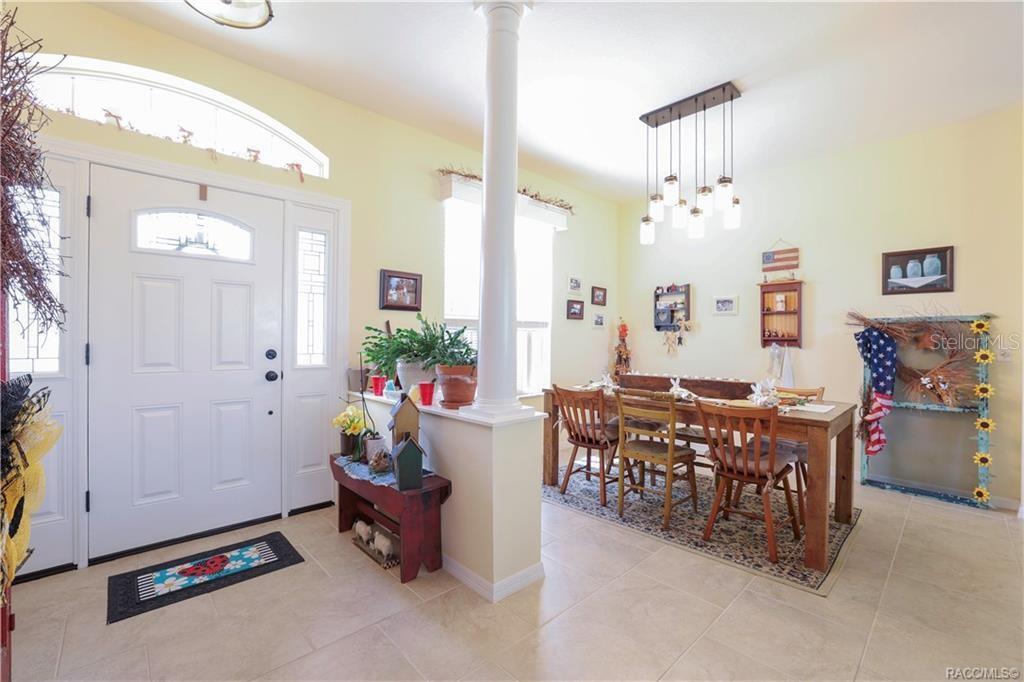 A dining area with a wooden table and chairs sits adjacent to a white entryway — 209 W REXFORD DRIVE, BEVERLY HILLS, FL