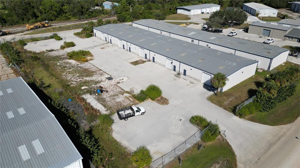 An aerial view shows a long industrial warehouse building with a paved lot and truck — 5469 WILLIAMSBURG DRIVE, PUNTA GORDA, FL