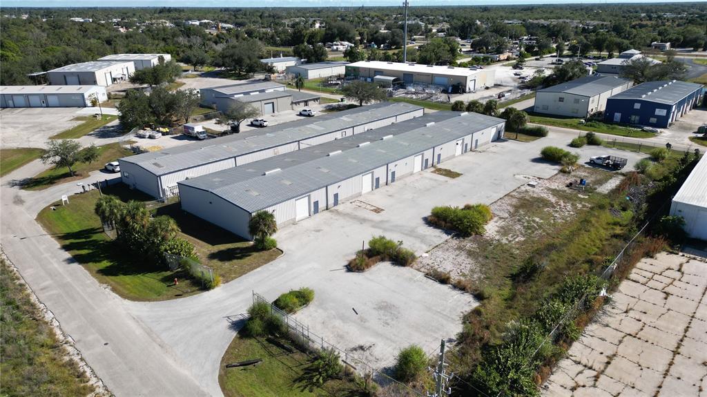 An aerial view shows two long, parallel industrial warehouse buildings with metal roofs and parking — 5469 WILLIAMSBURG DRIVE, PUNTA GORDA, FL