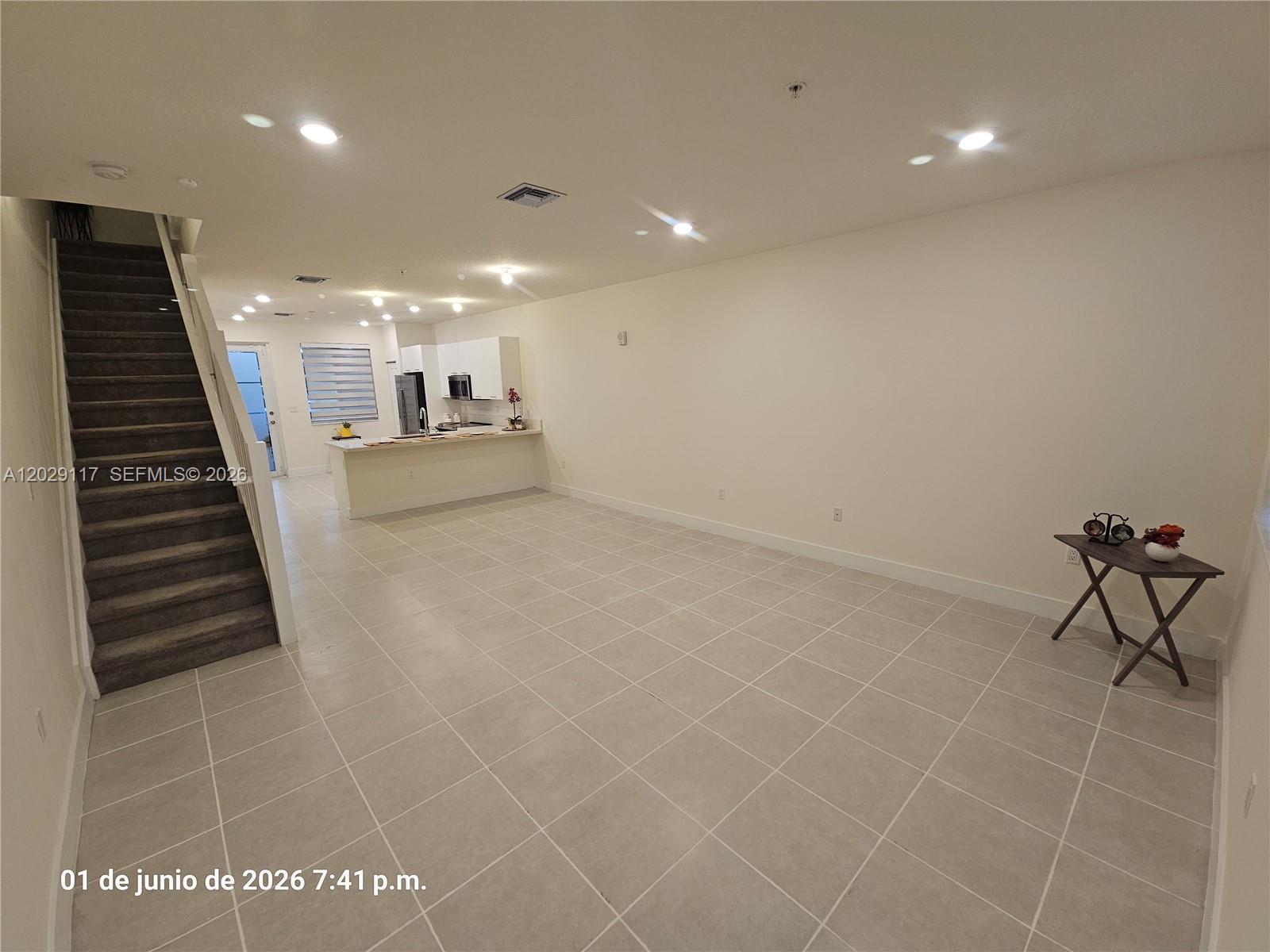 An open-concept living area features light tile flooring, a staircase, and a kitchen with white cabinetry — 6453 NW 102nd Path # 103, Doral FL 33178, DORAL, FL