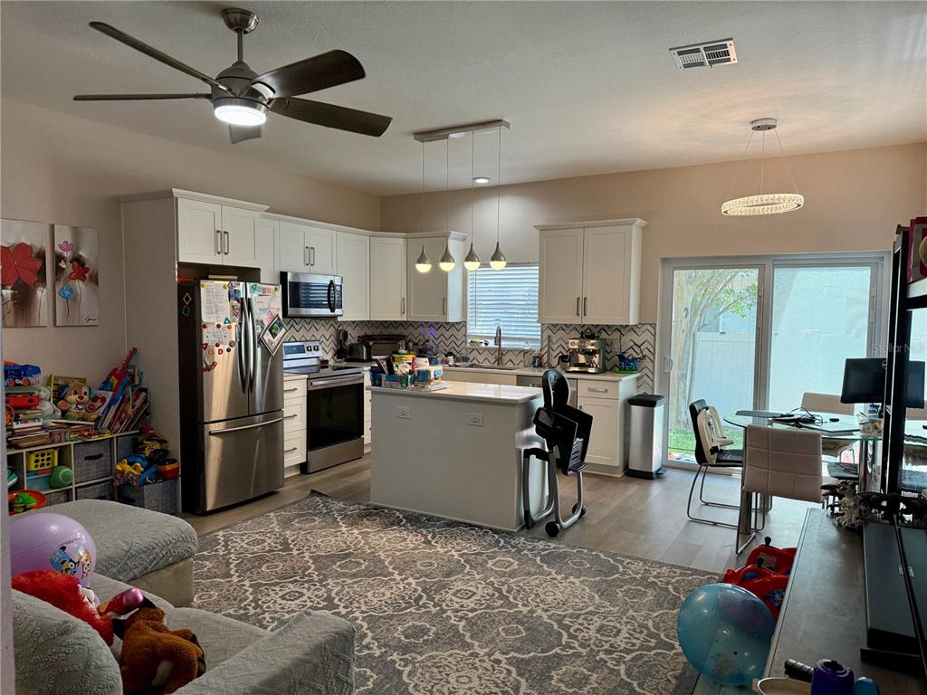 A hallway with light wood-look flooring leads toward a kitchen and sliding glass patio doors — 13201 OPAL COURT, LARGO, FL