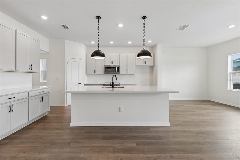 A modern kitchen features white cabinets, stainless steel appliances, and a large central island — 622 KINGSWOOD COURT, BRADENTON, FL
