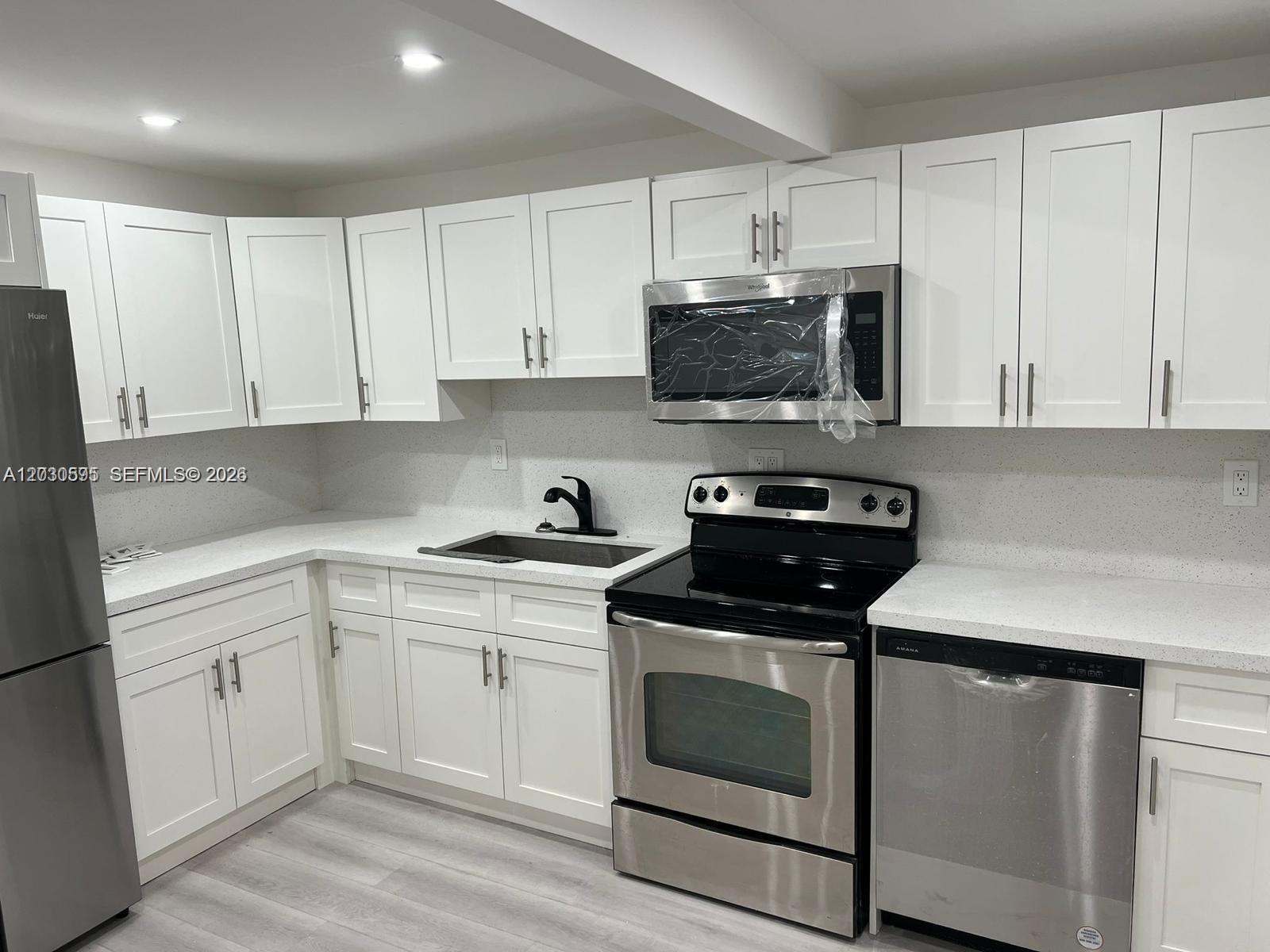 A kitchen features white shaker cabinets, stainless steel appliances, and light-colored quartz countertops — 428 NW 97th St # 0, Miami FL 33150, MIAMI, FL