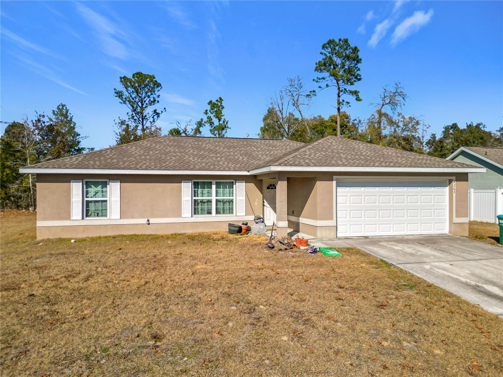 A single-story tan stucco house with a shingled roof and a two-car garage — 4263 SW 139TH PLACE, OCALA, FL
