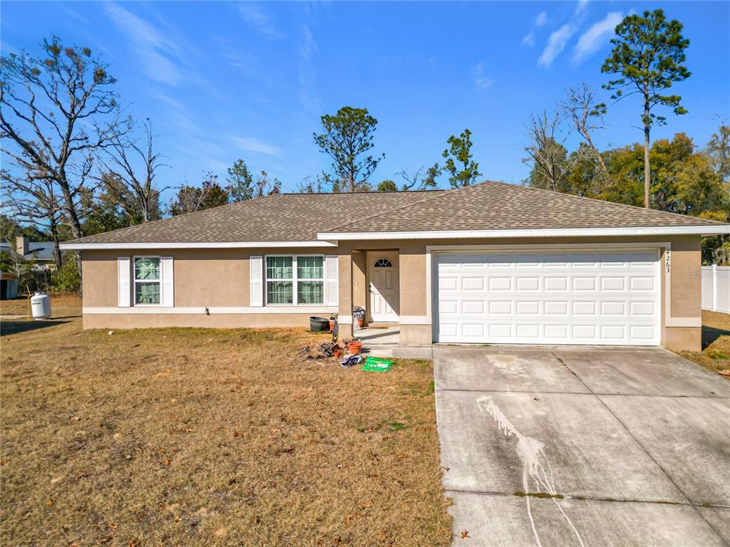 A single-story tan house with a two-car garage and a concrete driveway — 4263 SW 139TH PLACE, OCALA, FL
