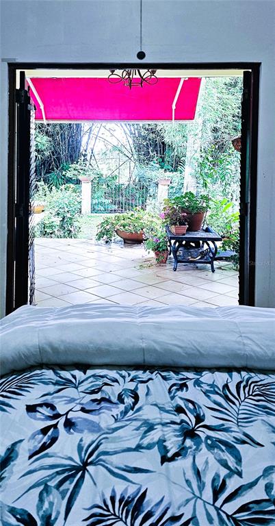 A view from a bed looking through open doors onto a tiled patio with potted plants — KM HM 0.2 ROAD 968, RIO GRANDE, PR