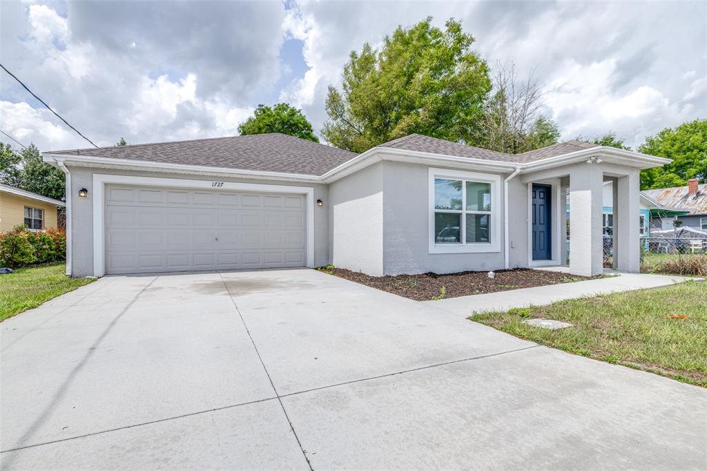 A single-story house with a gray exterior, a two-car garage, and a blue front door — 1727 SECOND STREET NE, WINTER HAVEN, FL